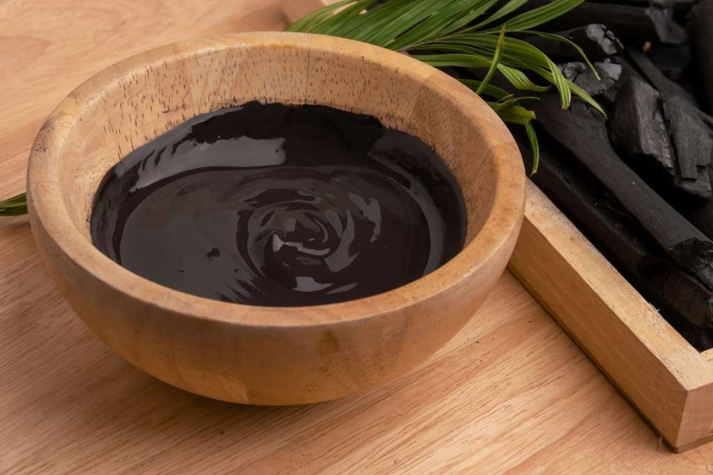 Charcoal cream in wooden bowl for facial spa treatment.