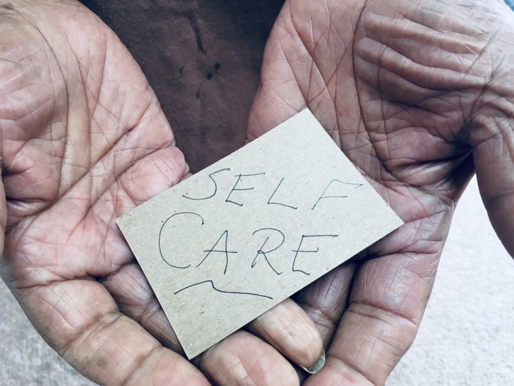 Man’s hands holding a note saying SELF CARE